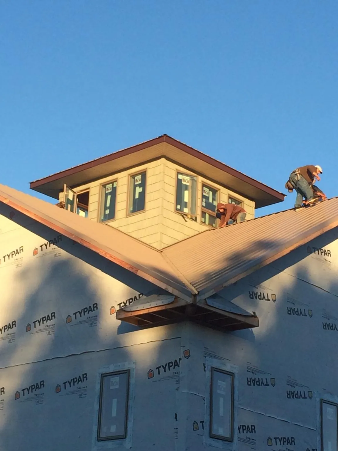 Roofers working around a rooftop cupola on a new metal roof at sunset — Roof Waterproofing in Anderson by Roofing Brothers